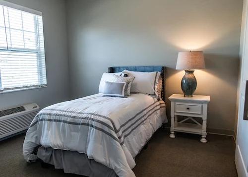 Comfortable bedroom with large window and cozy decor at Charter Senior Living of Hopkinsville in Hopkinsville, KY, designed for assisted living and memory care residents.
