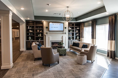 Cozy sitting area at Charter Senior Living of Hopkinsville in Hopkinsville, KY, featuring comfortable couches and chairs, a warm fireplace, and a TV—ideal for relaxation in assisted living and memory care.
