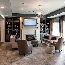 Cozy sitting area at Charter Senior Living of Hopkinsville in Hopkinsville, KY, featuring comfortable couches and chairs, a warm fireplace, and a TV—ideal for relaxation in assisted living and memory care.