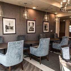 Elegant common area at Charter Senior Living of Hopkinsville in Hopkinsville, KY, featuring velvet chairs, stylish lighting, and spacious tables—designed for comfort in assisted living and memory care.