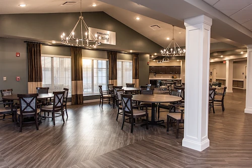 Bright and spacious dining room at Charter Senior Living of Hopkinsville in Hopkinsville, KY, featuring large round tables, elegant lighting, and windows for natural light—designed for comfort in assisted living and memory care.