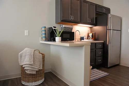 Modern assisted living apartment kitchenette at Charter Senior Living of Hopkinsville in Hopkinsville, KY, featuring a full-size refrigerator and microwave for senior convenience and independence.