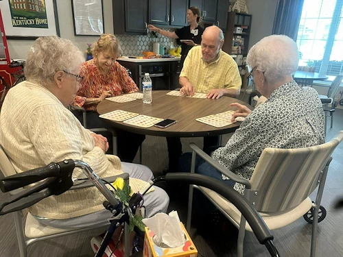 Seniors at Charter Senior Living of Hopkinsville in Hopkinsville, KY, gathered around a common table playing Bingo, fostering social connection in assisted living and memory care.
